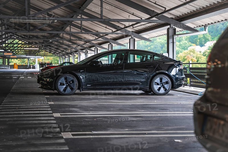Black car in a covered parking lot with a view of nature, Deer e- car sharing, Tesla Model 3, Calw, Germany