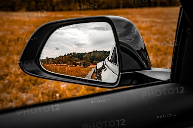 View through the side mirror of a car of a rural landscape with meadow and trees, Deer E-Carsharing, Tesla Model 3, Calw, Germany