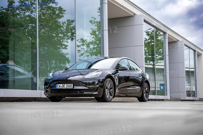 Black Tesla in front of a glass building with trees in the background, Deer e-Carsharing, Tesla Model 3, Calw, Germany