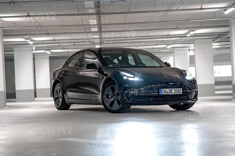 Black Tesla, headlights on, placed centrally in empty parking garage, Deer e-Carsharing, Tesla Model 3, Calw, Germany