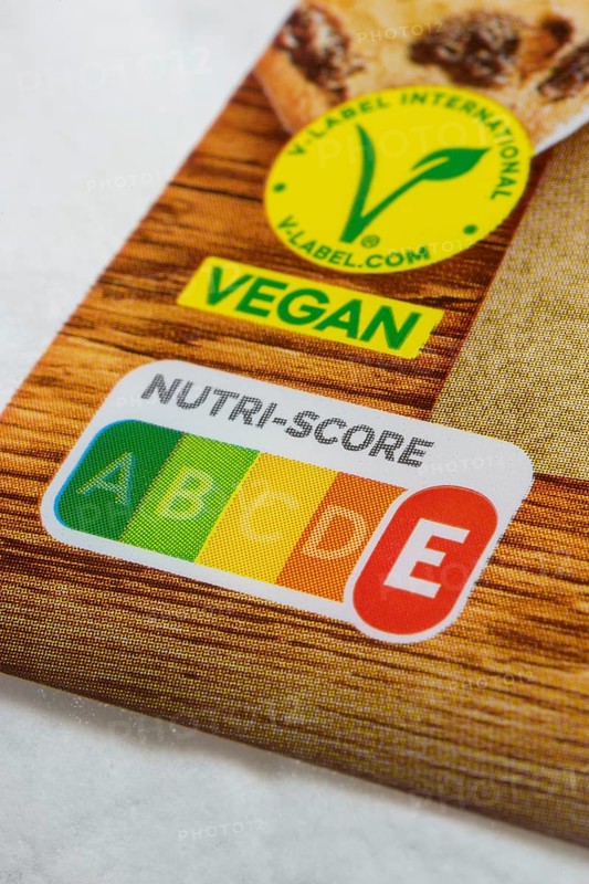 Food label with Nutri-Score E and vegan seal on wooden surface