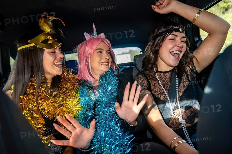 Young women friends celebrating a joyful costume party inside a car, expressing happiness and fun while enjoying the exciting new year's eve event together