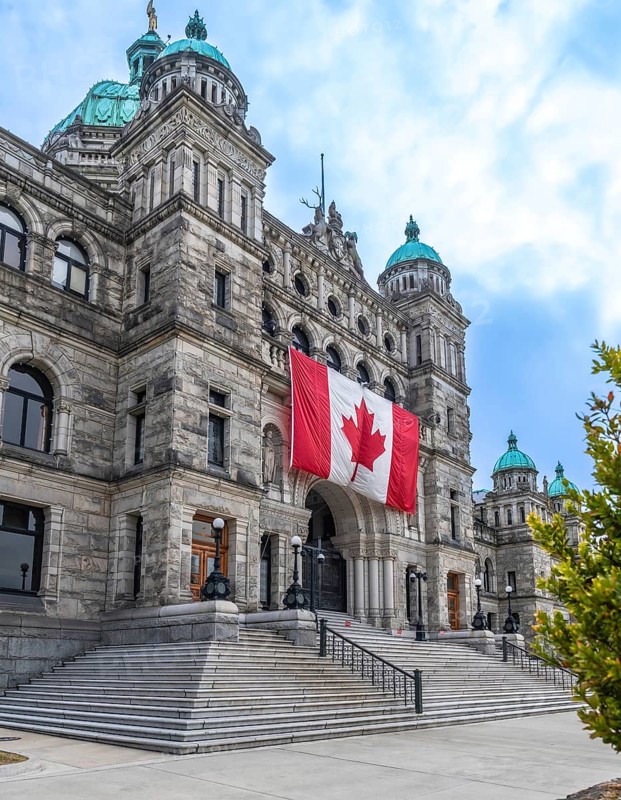Parliament buildings in victoria, british columbia, proudly displaying a large canadian flag, symbolize the province's political heart and rich cultural heritage in the capital city