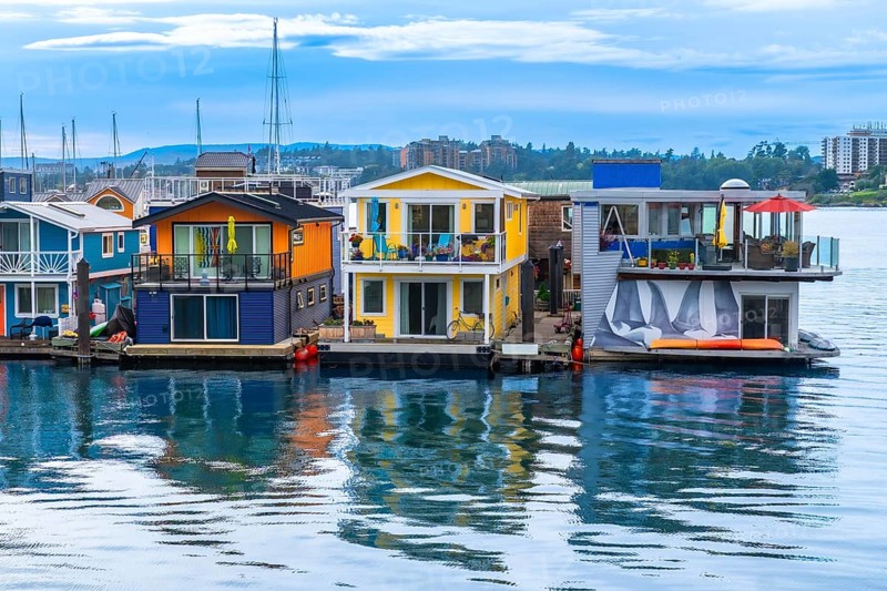 Vibrant houseboats create a picturesque scene, reflecting in the calm waters of fisherman's wharf park in victoria, british columbia, showcasing a unique and charming waterfront community