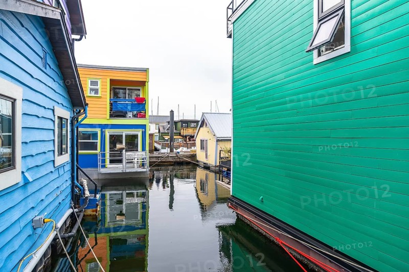 Fisherman's wharf park in victoria, british columbia, features vibrant floating homes reflecting in calm waters, creating a picturesque scene of this unique community