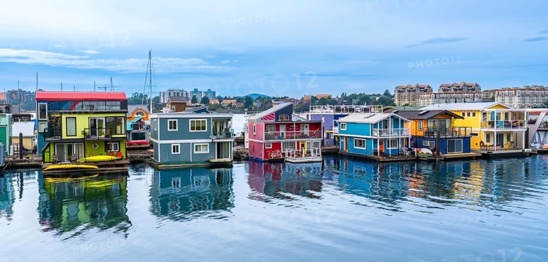 Fisherman's wharf park's vibrant houseboats create a picturesque scene, reflecting in the calm waters of victoria, british columbia, on a serene summer day