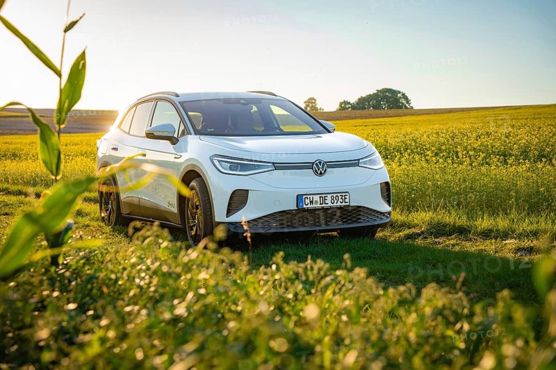 White car standing in a blooming field in sunlight, VW ID4 electric car, Deer Carsharing, Calw, Germany