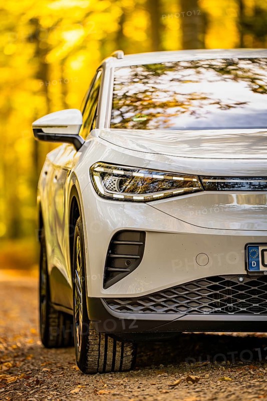 Close-up of a white car on a forest road in autumn, VW ID4 electric car, Deer Carsharing, Calw, Germany