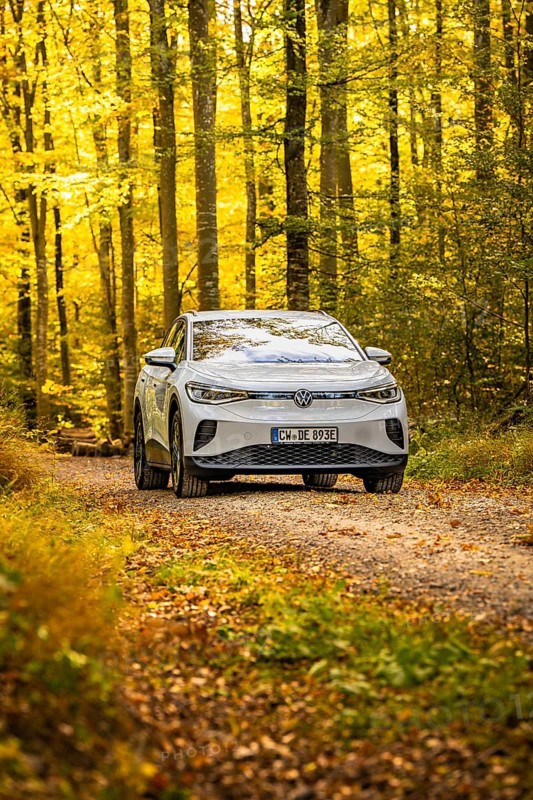 White car on a forest path surrounded by autumn leaves, VW ID4 electric car, Deer Carsharing, Calw, Germany
