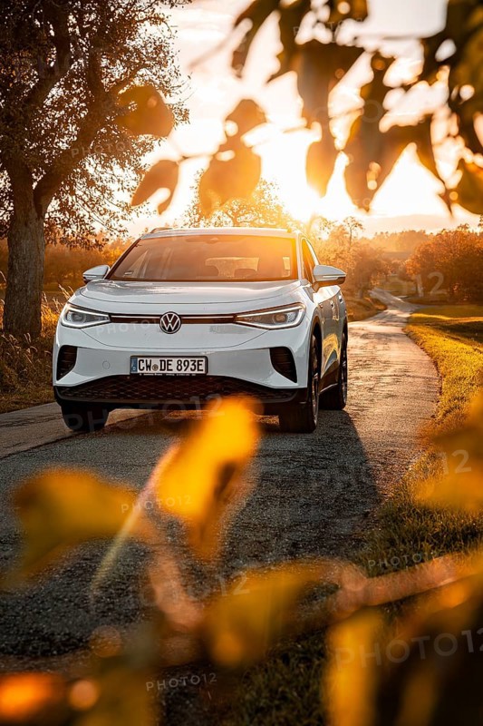 White car on a country road at sunset surrounded by leaves, VW ID4 electric car, Deer Carsharing, Calw, Germany