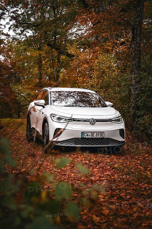 A white Volkswagen on a forest path covered with leaves in autumn, VW ID4 electric car, Deer Carsharing, Calw, Germany