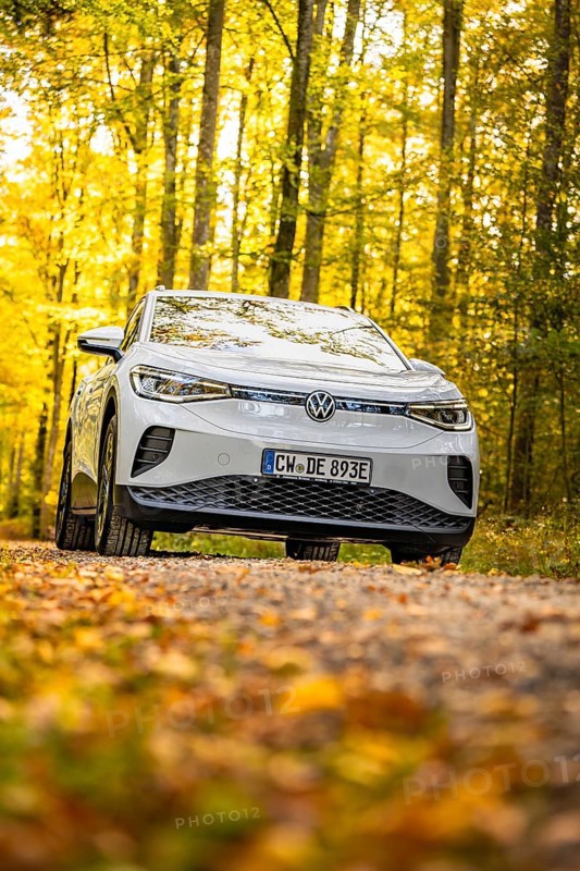 A white Volkswagen on a forest path with yellow autumn leaves, VW ID4 electric car, Deer Carsharing, Calw, Germany
