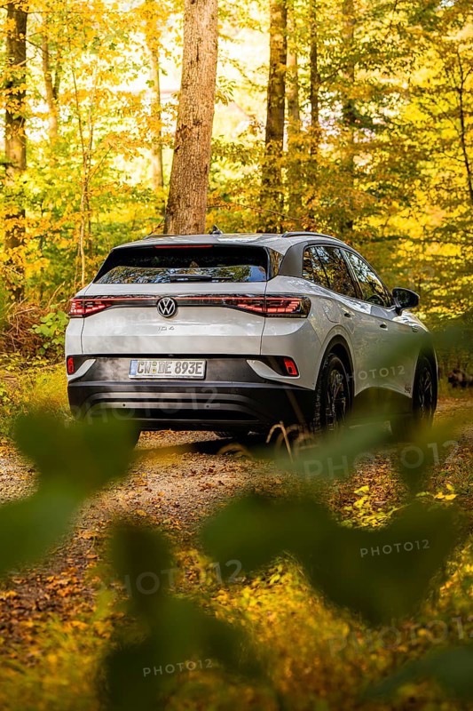 White car in autumn forest with yellow leaves on the ground, VW ID4 electric car, Deer Carsharing, Calw, Germany