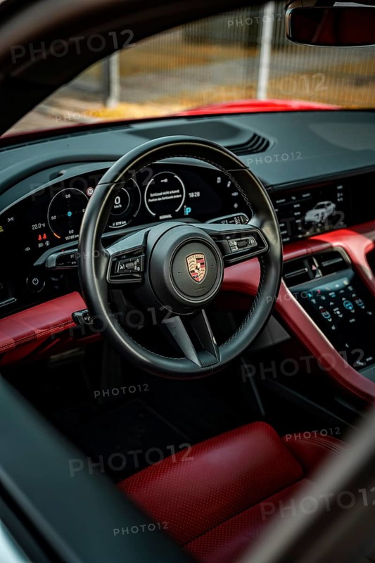 Modern car interior with red and black interior, showing steering wheel and instruments, Porsche Taycan, Deer Carsharing, Calw, Germany