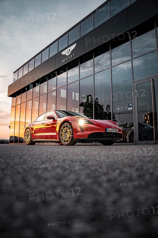 Red sports car in front of a Bentley building at sunset, Porsche Taycan, Deer Carsharing, Calw, Germany