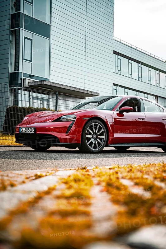 Modern red sports car in front of an office building on the street in daylight, Porsche Taycan, Deer Carsharing, Calw, Germany