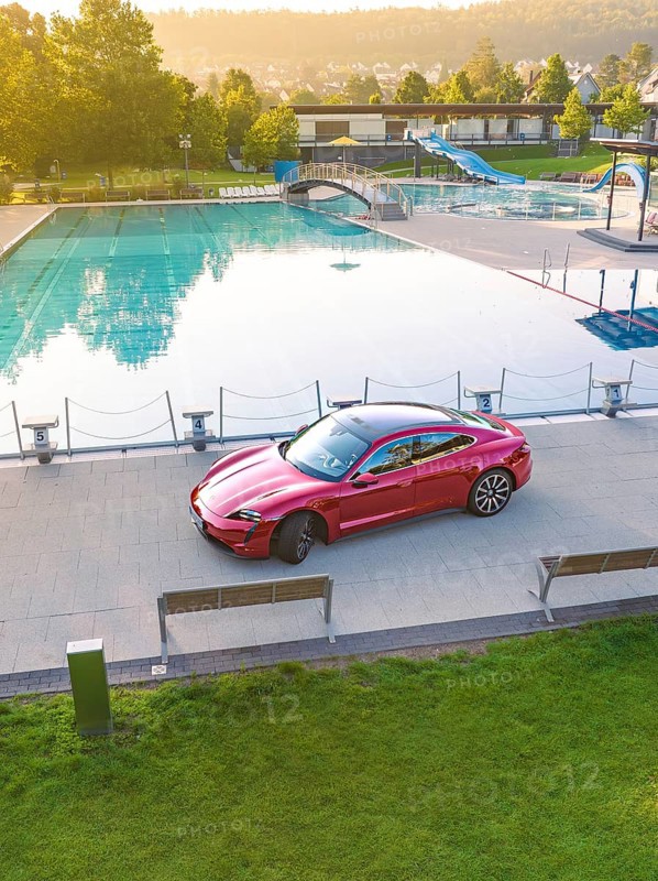 Red car parked next to swimming pool in urban area, Porsche Taycan, deer car sharing. Calw, Germany