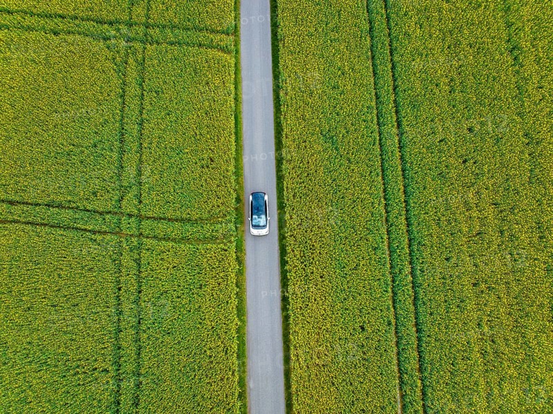Aerial view of a car on a road between large fields, ID3 VW, deer car sharing. Calw, Germany