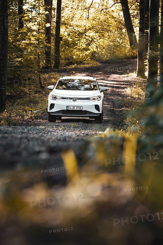 A car is parked on a forest path surrounded by autumn atmosphere and sun rays, VW ID4 electric car, deer car sharing, Calw, Germany
