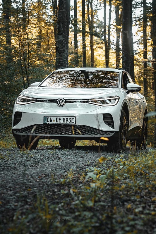 A white car is parked on a gravel path in the forest at dusk, VW ID4 electric car, Deer Carsharing, Calw, Germany