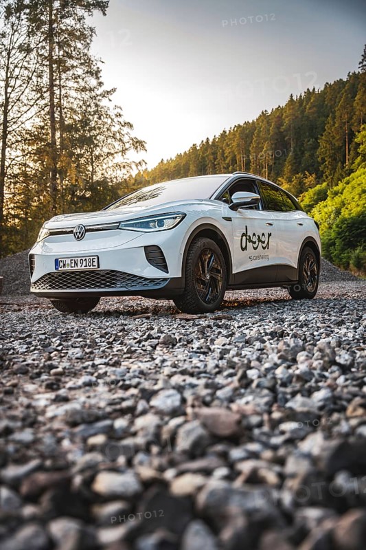 A car on a gravel path on the edge of a forest at sunset, VW ID4 electric car, Deer Carsharing, Calw, Germany