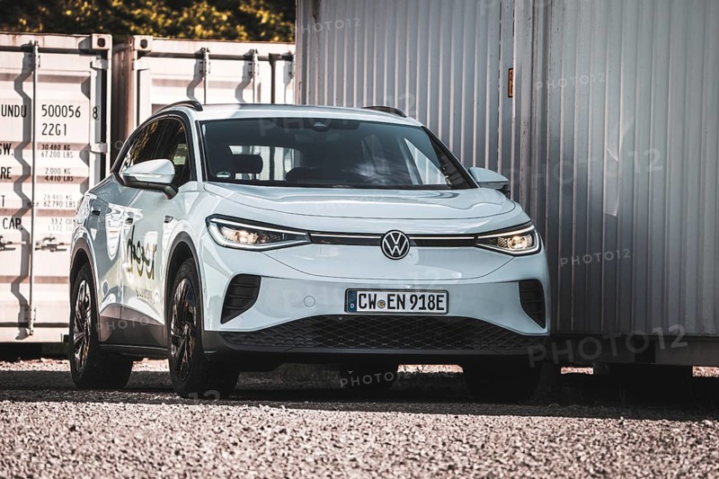 A white car is parked next to several containers on a gravel field, VW ID4 electric car, Deer Carsharing, Calw, Germany