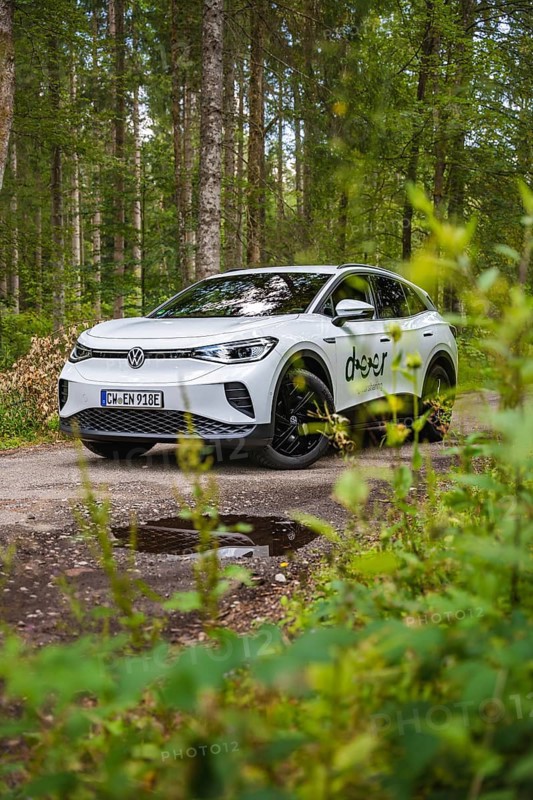 White car in the forest surrounded by green leaves, VW ID4 electric car, Deer Carsharing, Calw, Germany