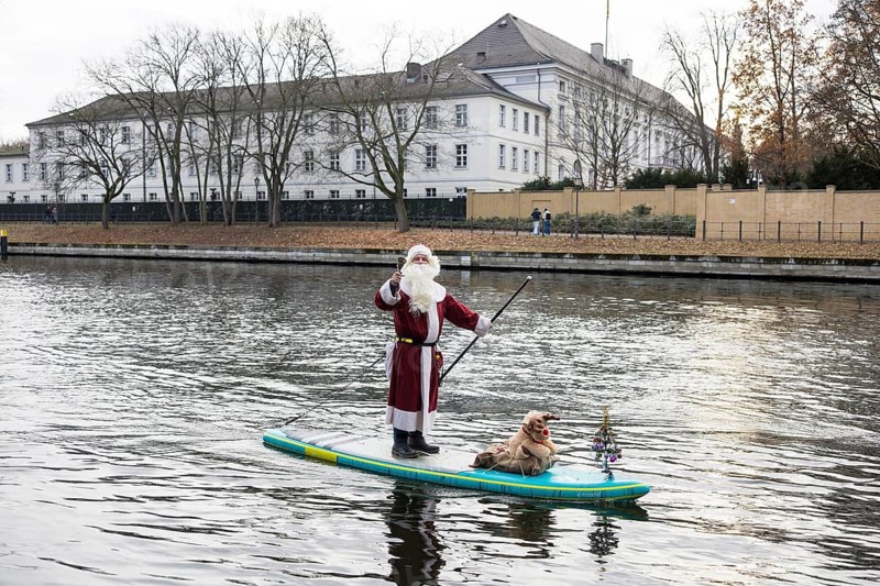 A water sports enthusiast dressed up as Santa Claus rides a SUP on the Spree in front of Bellevue Palace in Berlin on 30.11.2025