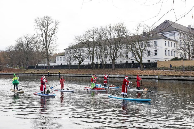 Water sports enthusiasts dressed up as Santa Claus ride SUPs on the Spree in front of Bellevue Palace in Berlin on 30.11.2025