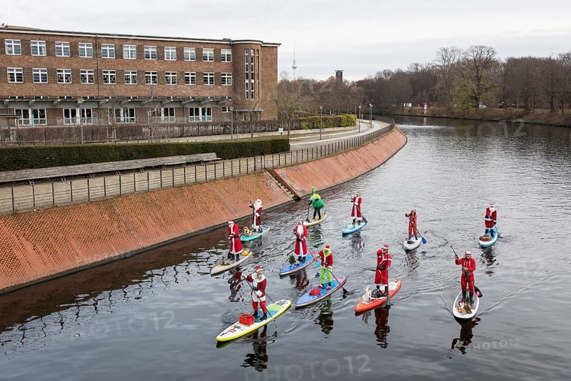 Water sports enthusiasts dressed up as Santa Claus ride SUPs on the Spree am Park at the presidential triangle in Berlin on 30.11.2025