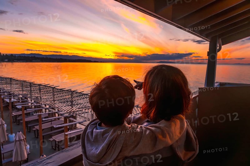 Mother and son bonding while enjoying breathtaking golden sunset view over qualicum beach on vancouver island, creating cherished family memories during summer vacation