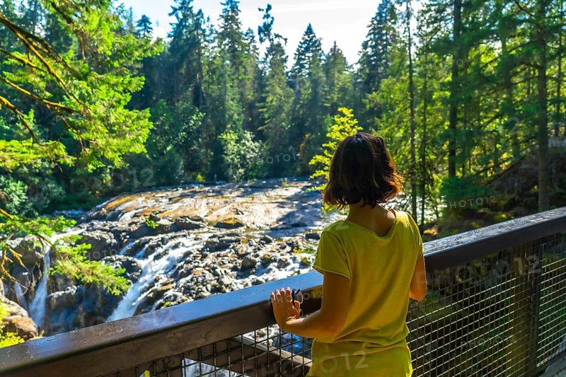 Female tourist admiring englishman river falls in vancouver island, british columbia, canada, enjoying the beautiful nature during summer holidays