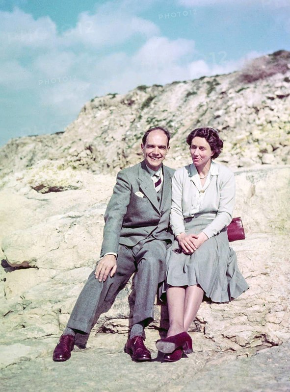 Portrait of smartly dressed man and woman, couple sitting on rocks at the seaside c 1956