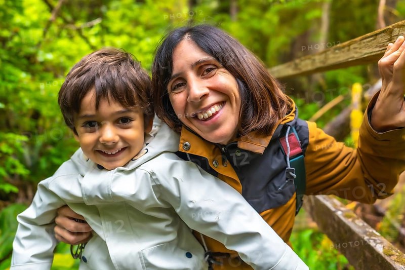 Mother and son are enjoying a hike in a lush rainforest, sharing a happy moment together surrounded by nature's beauty in ucluelet, vancouver island, canada