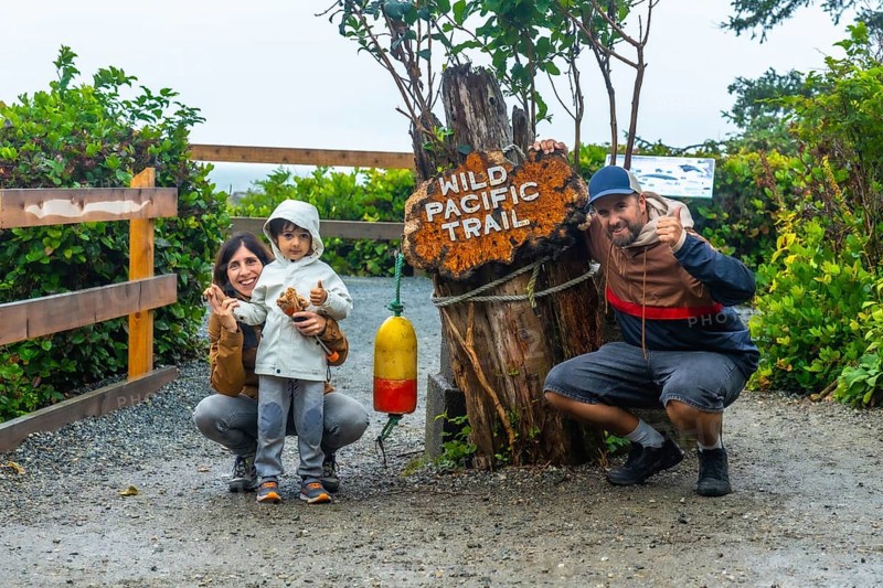 Happy family posing for a photo at the entrance of the wild pacific trail in ucluelet, british columbia, canada, enjoying a day outdoors surrounded by nature