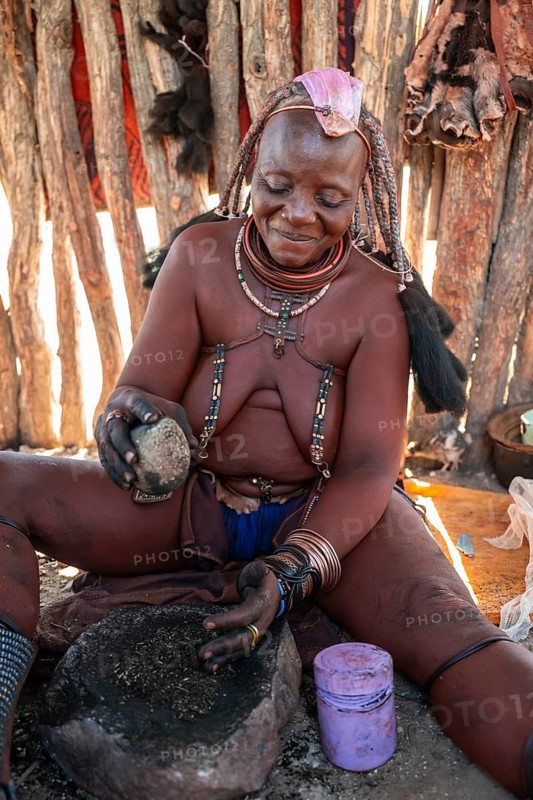 Himba woman grinding grain on a stone, Himba village, Kaokoveld, Kunene, Namibia
