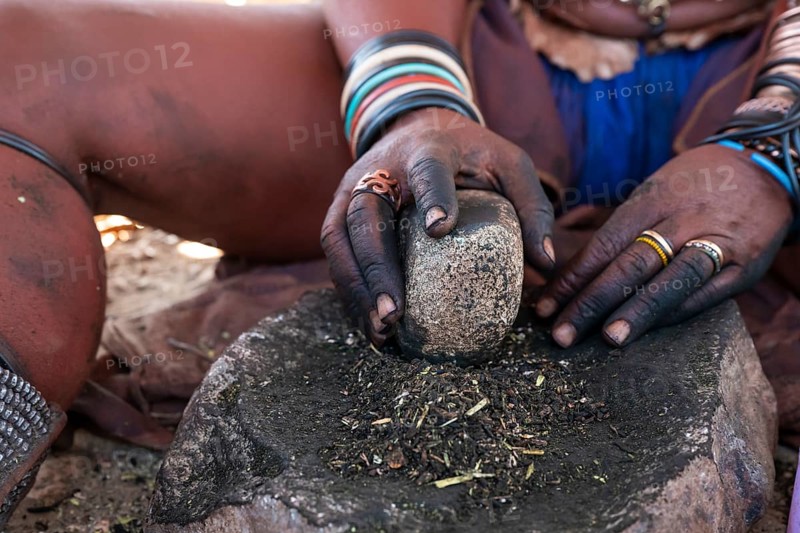 Himba woman grinding grain on a stone, Himba village, Kaokoveld, Kunene, Namibia