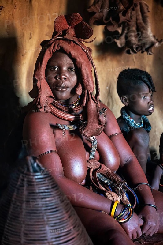 Himba woman sitting with baby, Himba perfume, scented smoke from burning plants, Himba village, Kaokoveld, Kunene, Namibia