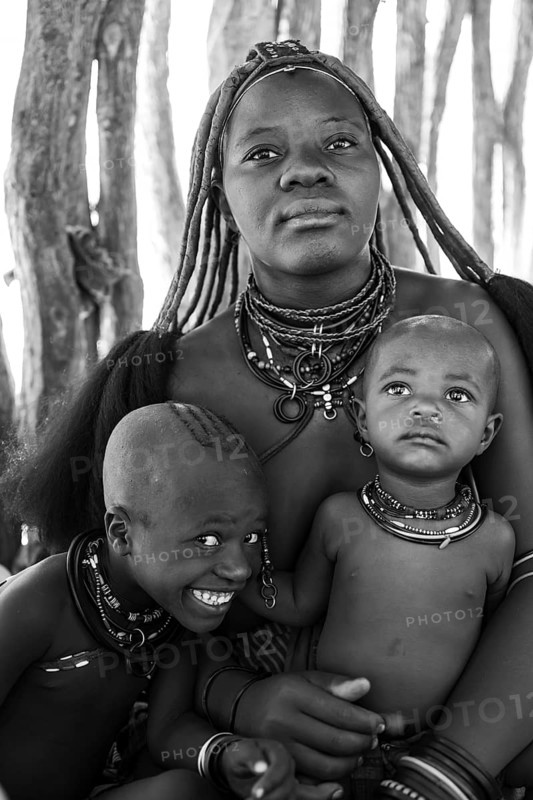 Black and white, Himba woman with baby and grinning child, traditional Himba village, Kaokoveld, Kunene, Namibia