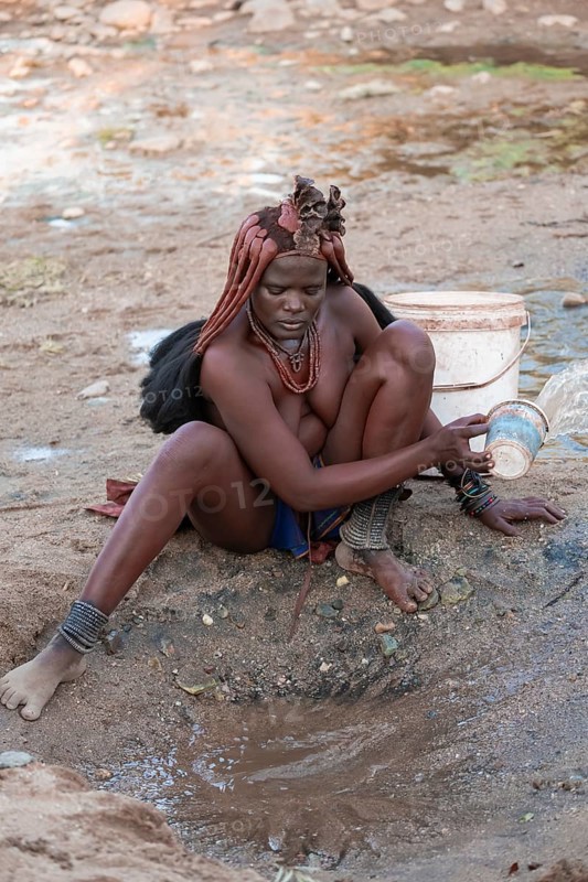 Himba scooping water at water source, traditional Himba, Kaokoveld, Kunene, Namibia