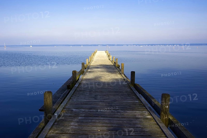 A long wooden walkway leads into the still water of a huge lake under a clear sky, Steinhude Steinhuder Meer