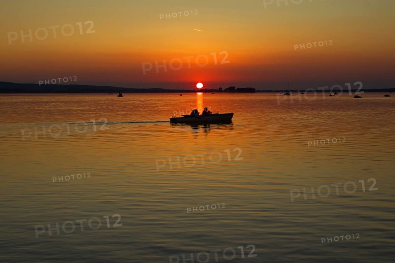Sunset with boat in the middle of the lake, calm waters, peaceful view, Steinhude Steinhuder Meer