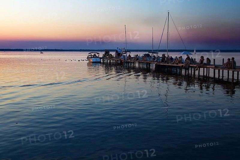 People sitting on a pier at sunset, boats at dusk, relaxed atmosphere, Steinhude, Steinhuder Meer