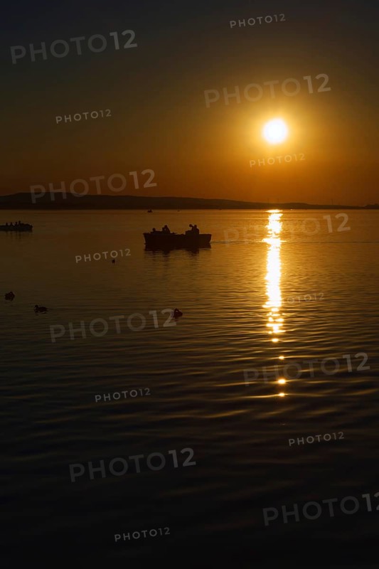 Sunset over the Steinhuder Meer with boat and reflections, quiet atmosphere, Steinhude