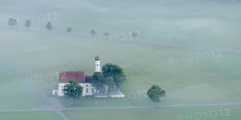 St. Coloman pilgrimage church in front of sunrise in autumn fog, Königswinkel, Ostallgäu, Allgäu, Bavaria, Germany