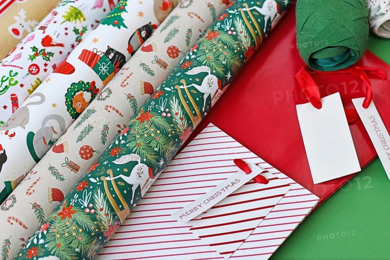 Close up of Christmas wrapping material like paper, bags and ribbons on green background