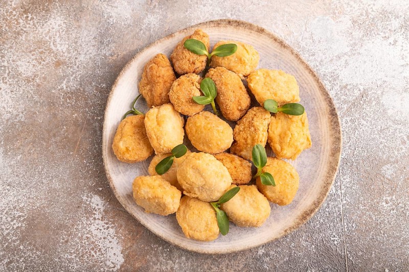 Fried crispy Chicken Nuggets with ketchup, microgreen on brown concrete background. top view, flat lay, close up