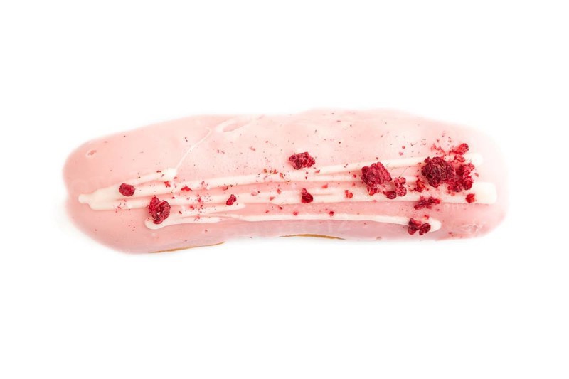 Glazed pink Eclair on brown concrete isolated on white, top view, flat lay, close up