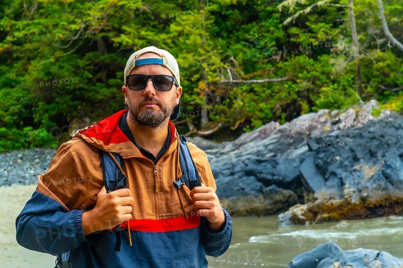 Male tourist wearing sunglasses and a baseball cap enjoying the stunning beaches of tofino, a renowned travel destination on vancouver island, british columbia
