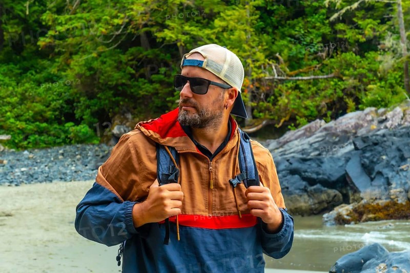 Male tourist wearing sunglasses and a baseball cap, exploring the beautiful beaches and lush rainforests of tofino, a popular travel destination on vancouver island, british columbia, canada